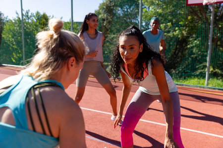 Focused diverse female friends playing basketball at basketball court. Sport, activity, friendship...
