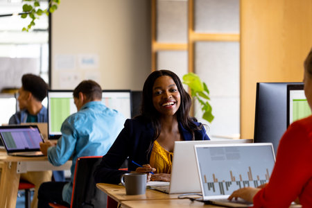 Happy casual businesswoman and diverse colleagues working using computers in office. Casual office,...