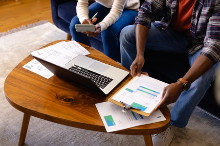 Low section of african american couple doing paperwork using laptop at home. Lifestyle,...
