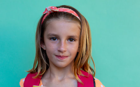 Portrait of happy caucasian schoolgirl with band over blue background at elementary school....