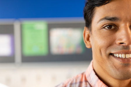 Half portrait of happy biracial male teacher with in elementary school classroom with copy space. Teaching, education, childhood, development, learning and school, unaltered.の写真素材