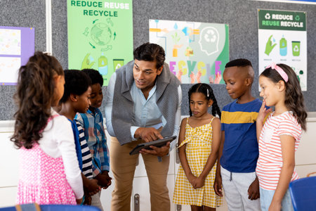 Biracial male teacher using tablet teaching children in elementary school class. Technology, education, childhood, development, learning and elementary school, unaltered.の写真素材