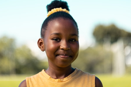 Portrait of african american schoolgirl smiling in sports field at elementary school. School,...