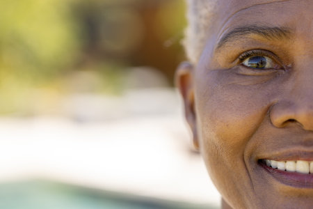 Half portrait of happy senior biracial woman smiling in sunny garden, copy space. Retirement, health, relaxation and senior lifestyle, unaltered.の写真素材