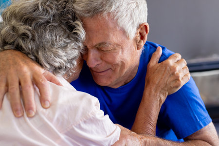 Distressed senior caucasian couple embracing and crying in group therapy session. Senior lifestyle,...