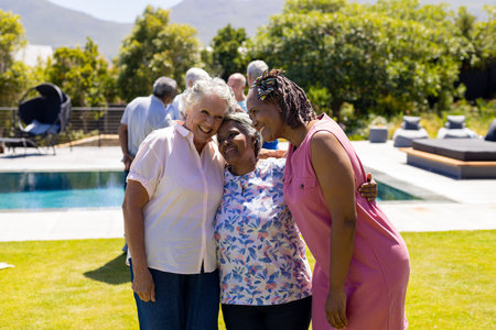 Happy senior diverse female friends embracing and smiling in garden. Senior lifestyle, friendship and relaxation, retirement, unaltered.の写真素材