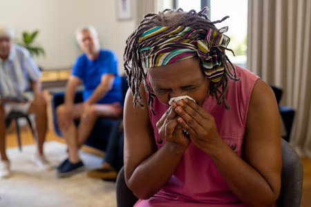 Distressed senior biracial woman holding tissue and crying in group therapy session. Senior lifestyle, friendship and support, retirement, unaltered.の写真素材
