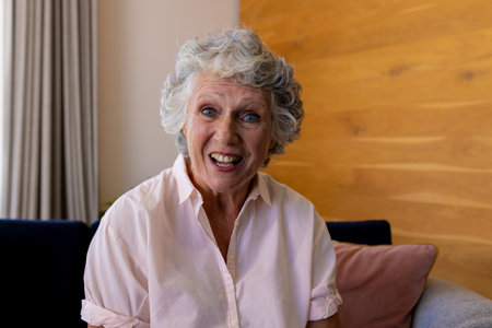 Happy senior caucasian woman making video call sitting on sofa smiling and talking at home. Senior...