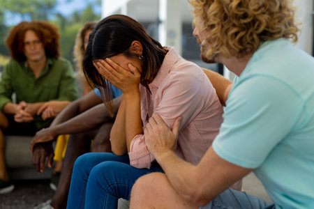Group of diverse people sitting on sofa, talking and crying in group therapy session. Lifestyle, friendship and support, togetherness, unaltered.の写真素材