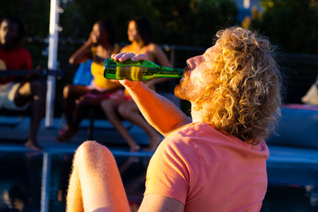 Happy diverse group of friends having pool party and drinking beer in garden. Lifestyle, friendship...