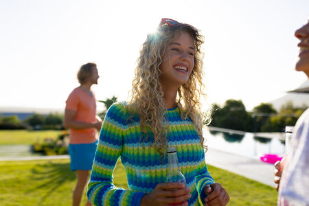 Happy diverse group of friends having party, drinking beer and talking in garden. Lifestyle,...