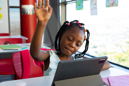 Happy african american schoolgirl having tablet video call in classroom at elementary school....