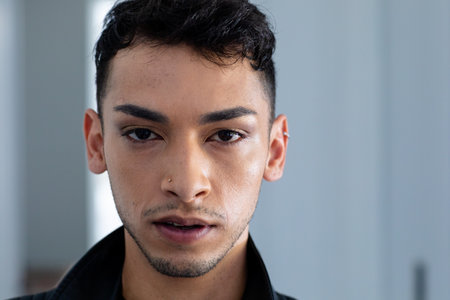 Portrait of biracial transgender man wearing biker jacket, looking at camera. Gender, fashion and lifestyle, unaltered.の写真素材