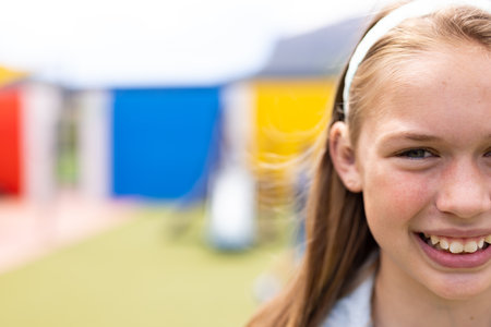 Half face portrait of smiling caucasian schoolgirl in schoolyard, with copy space. Education, inclusivity, elementary school and learning concept.の写真素材