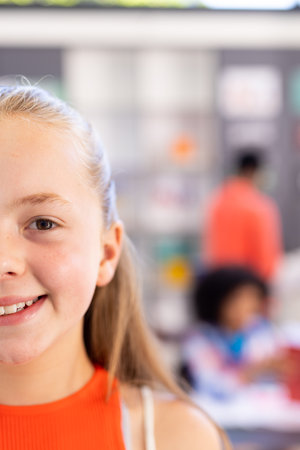 Half face portrait of smiling caucasian schoolgirl in classroom, copy space. Education, inclusivity, elementary school and learning concept.の写真素材