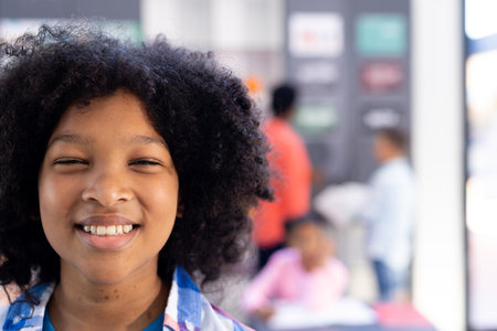 Portrait of happy, smiling biracial schoolgirl in classroom copy space. Education, inclusivity, elementary school and learning concept.の写真素材