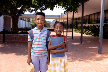 Portrait of happy african american schoolchildren standing in school yard. Education, childhood, elementary school and learning concept.の写真素材