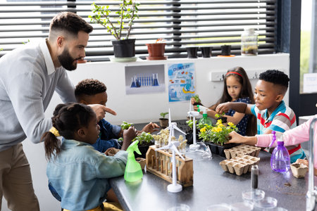 Diverse elementary schoolchildren and male teacher studying plants together in school class....