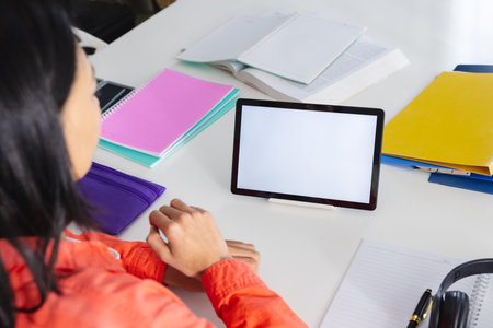 Image of biracial woman using tablet with copy space on screen sitting at desk. Working from home...