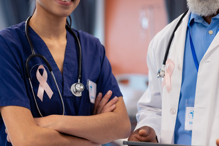 Midsection of diverse female and senior male doctor with cancer ribbons in hospital ward, copy space. Hospital, medical and healthcare services.の写真素材