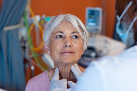 Diverse senior male doctor examining the throat of smiling senior female patient, copy space. Hospital, medical and healthcare services.の写真素材