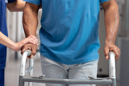 Modsection of diverse female doctor helping senior male patient use walking frame in hospital. Hospital, medical and healthcare services.の写真素材