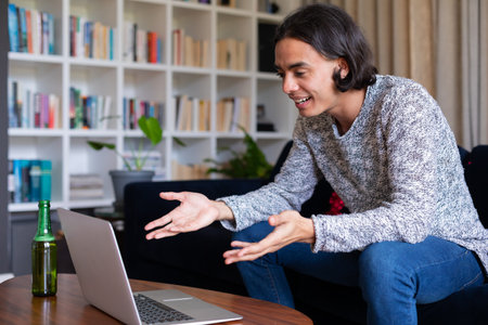 Happy biracial man sitting on sofa, using laptop for video call. Spending quality time at home...