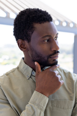 African american businessman thinking and touching his chin outside modern office. Global business,...
