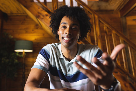 Portrait of happy african american man spending time in log cabin and having video call. Log cabin,...