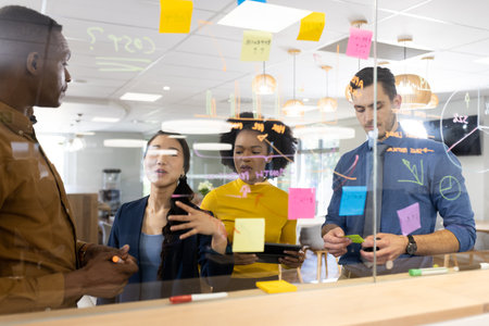 Diverse people in office brainstorming and writing on glass board. Business, corporation, working in office concept.の写真素材