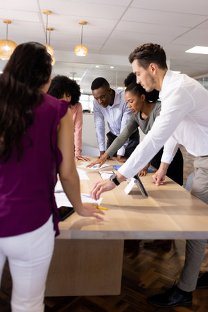 Vertical image of diverse female and male businesspeople talking and working. Business, corporation, working in office and cooperation concept.の写真素材