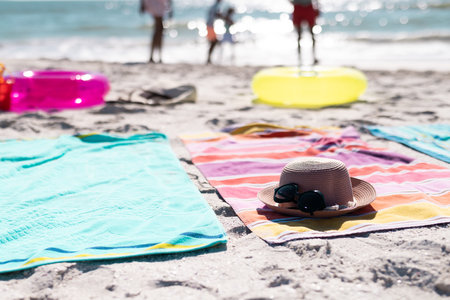 Sunglasses with hat placed on towels over sandy beach during sunny day. Copy space, unaltered, protection, vacation, fashion, picnic and summer concept.の写真素材