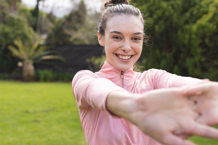 Portrait of happy caucasian woman practicing yoga and stretching in garden. Lifestyle, relaxation and domestic life, unaltered.の写真素材
