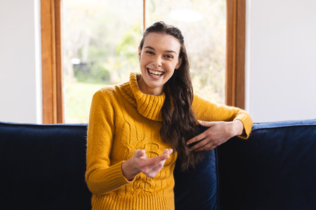 Happy caucasian woman sitting on sofa having video call at home. Lifestyle, communication, video...