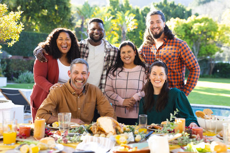 Happy diverse male and female friends posing during thanksgiving celebration meal in sunny garden. Celebration, friendship, patriotism, american culture and tradition, unaltered.の写真素材