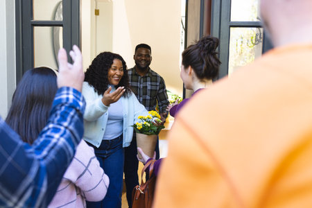 Happy african american couple receiving guests in sunny house. Lifestyle,relaxation,free time and domestic life, friendship, unaltered.の写真素材
