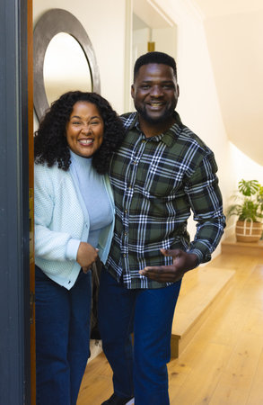 Happy african american couple standing in doorway and smiling on sunny day. Lifestyle,relaxation,free time and domestic life,relationship, unaltered.の写真素材
