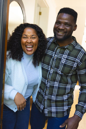 Happy african american couple standing in doorway and laughing on sunny day. Lifestyle,relaxation,free time and domestic life, relationship,unaltered.の写真素材