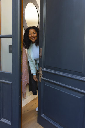 Happy african american woman opening door and smiling on sunny day. Lifestyle,relaxation,free time and domestic life, unaltered.の写真素材