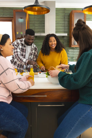 Happy diverse male and female friends preparing meal and drinking drinks in kitchen. Cooking, food, lifestyle, friendship and domestic life, unaltered.の写真素材