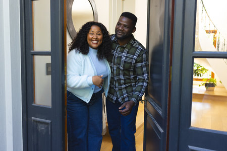 Happy african american couple standing in doorway and smiling on sunny day. Lifestyle,relaxation,free time and domestic life, relationship,unaltered.の写真素材