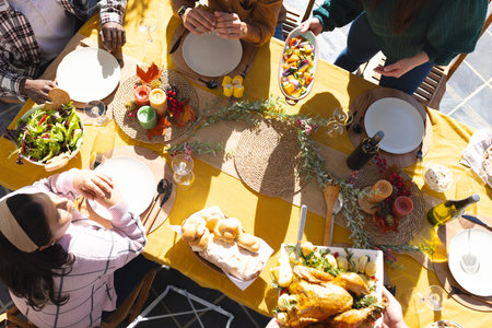 Happy diverse male and female friends serving thanksgiving celebration meal in sunny garden. Celebration, friendship, patriotism, american culture and tradition, unaltered.の写真素材