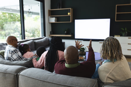 African american parents, son, daughter and grandparents watching tv with copy space, slow motion. Entertainment, home, family, togetherness, domestic life and lifestyle, unaltered.の写真素材