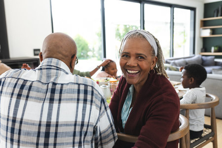 Portrait of african american grandmother with family at thanksgiving dinner table. Thanksgiving, celebration, tradition, meal, home, family, togetherness and lifestyle, unaltered.の写真素材