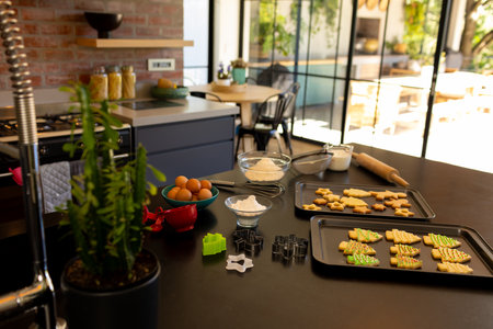 Luxury, sunny kitchen with freshly baked christmas cookies in baking trays on worktop. Cooking,...