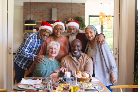 Happy diverse group of senior friends posing to picture at christmas dinner in sunny dining room. Retirement, friendship, christmas, celebration, meal, senior lifestyle, communication unaltered.の写真素材