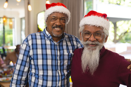 Happy diverse senior male friends in santa hats embracing at christmas meal. Retirement, christmas,...