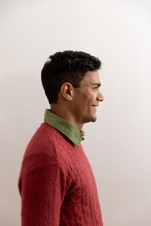 Happy biracial man with black hair over white wall at home. Lifestyle and domestic life, unaltered.の写真素材