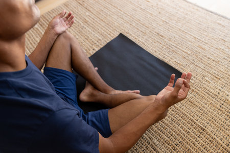 Close up of biracial man doing yoga and meditating at home. Self care, lifestyle and domestic life.の写真素材
