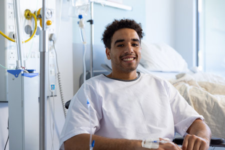Portrait of happy biracial male patient in wheelchair in sunny hospital room. Medicine, healthcare and medical services, unaltered.の写真素材